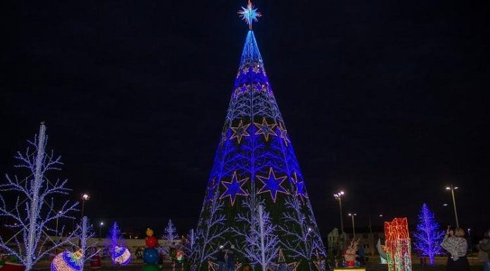 estrutura de ávore de natal iluminada com estrelas e outros elementos de decoração em volta