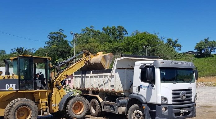 retroescavadeira despejando em caminhão em área de terra