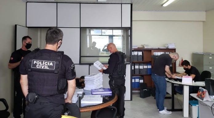 Policiais Civis analisando papeis dentro de uma sala