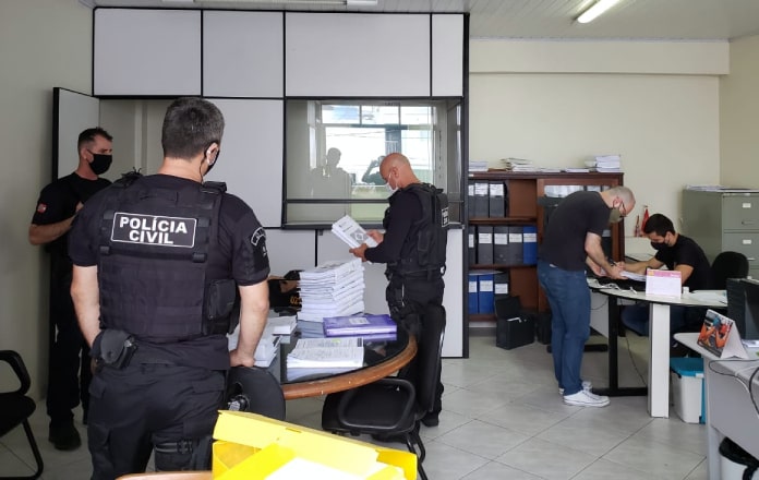 Policiais Civis analisando papeis dentro de uma sala