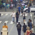 pessoas andando em rua do centro de florianópolis, com motos estacionadas em um lado; calçadão ao fundo