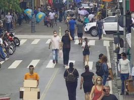 pessoas andando em rua do centro de florianópolis, com motos estacionadas em um lado; calçadão ao fundo