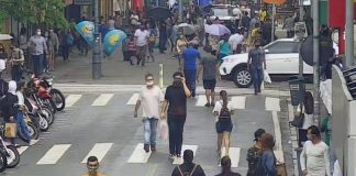 pessoas andando em rua do centro de florianópolis, com motos estacionadas em um lado; calçadão ao fundo