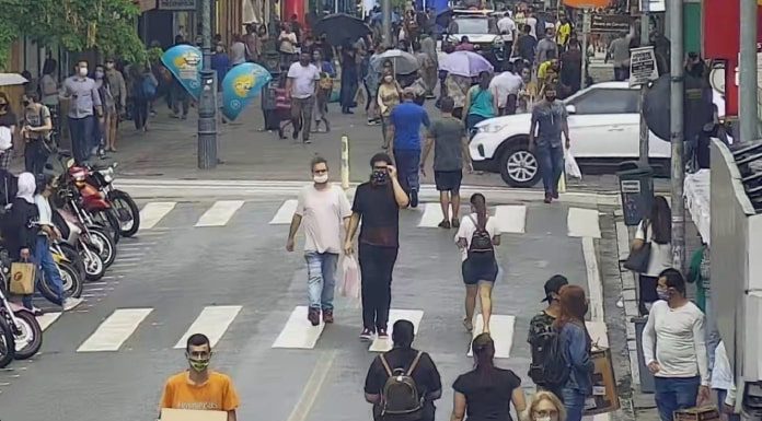 pessoas andando em rua do centro de florianópolis, com motos estacionadas em um lado; calçadão ao fundo