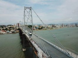 foto aérea da ponte hercílio luz com ônibus passando e continente ao fundo