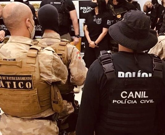 policiais civis e militares reunidos vistos de costas com inscrições dos grupos nos coletes