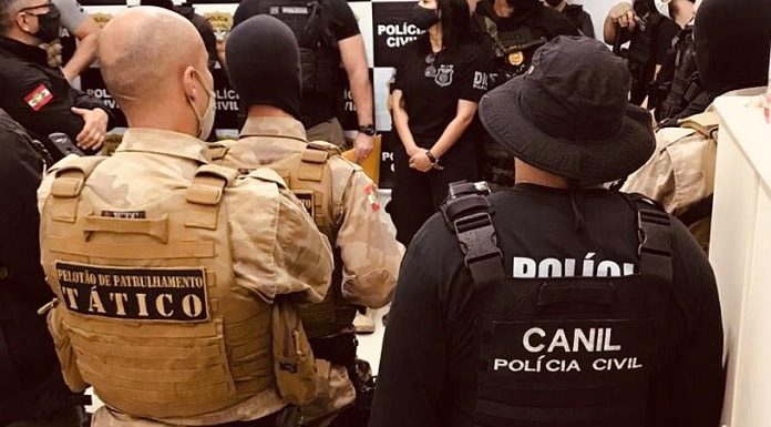 policiais civis e militares reunidos vistos de costas com inscrições dos grupos nos coletes