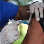 vacinas: pessoa usando luva aplica dose de vacina em braço de uma senhora