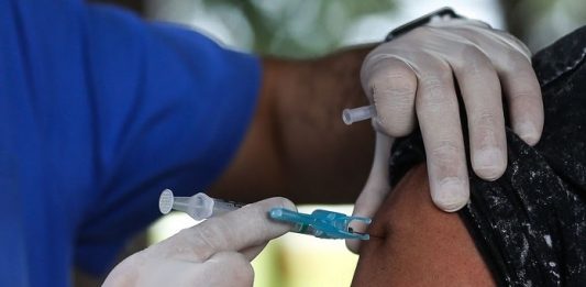Pesquisadores da UFSC falam da importância e desafios da pesquisa e desenvolvimento em vacinas vacinas: pessoa usando luva aplica dose de vacina em braço de uma senhora