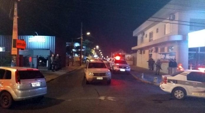 carros de polícia, viaturas e policias em esquina portanto armas próximos à delegacia para onde foram levados os suspeitos de participaram do assalto em criciúma