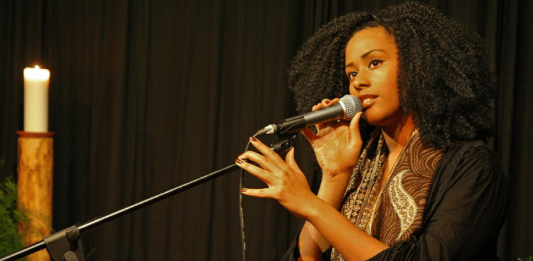 Lei Aldir Blanc irá disponibilizar R$ 1,2 milhão para projetos em São José Mulher sentada cantando; uma mão no pedestal e outra no microfone
