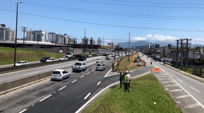 aumentado o acesso da Via Expressa para a BR 101 - faixa nova de asfalto ao lado da rodovia, com homens no canteiro e carros passando