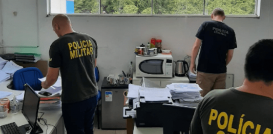 Um policial civil, um militar e um da perícia criminal vendo documentos