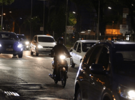 Carros e uma moto de noite nas ruas de Criciúma