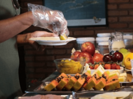 Uma pessoa servindo sua comida com luvas em um hotel