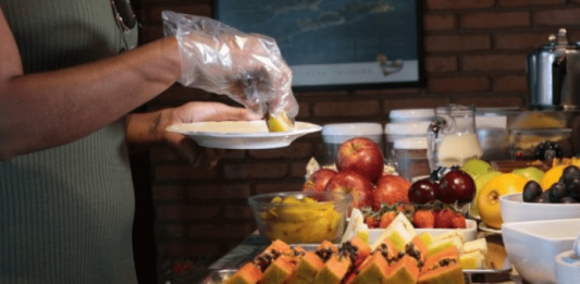 Governo publica portarias para regrar hotéis, casas noturnas e eventos sociais Uma pessoa servindo sua comida com luvas em um hotel