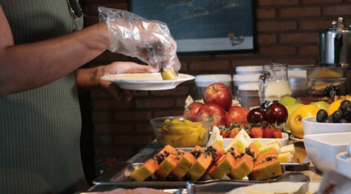 Uma pessoa servindo sua comida com luvas em um hotel