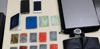 Cartões de crédito clonados, carteiras, celulares e uma placa da Polícia Civil de Santa Catarina em cima da mesa