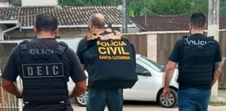 operação terra limpa: três policias vistos andando de costas saindo de estacionamento; um deles carrega grande malote da polícia civil