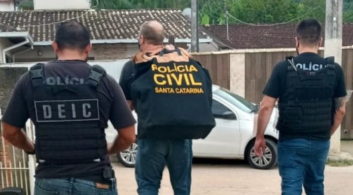 operação terra limpa: três policias vistos andando de costas saindo de estacionamento; um deles carrega grande malote da polícia civil