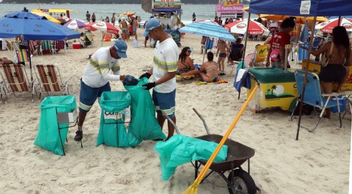 dois garis da comcap fazem coleta de lixo nas praias de florianópolis, na imagem na praia do campeche; guarda-sóis em volta