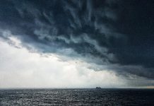 Defesa Civil alerta para tempestade na região sul do brasil - nuvem carregada sobre o oceano, com pequena embarcação no horizonte