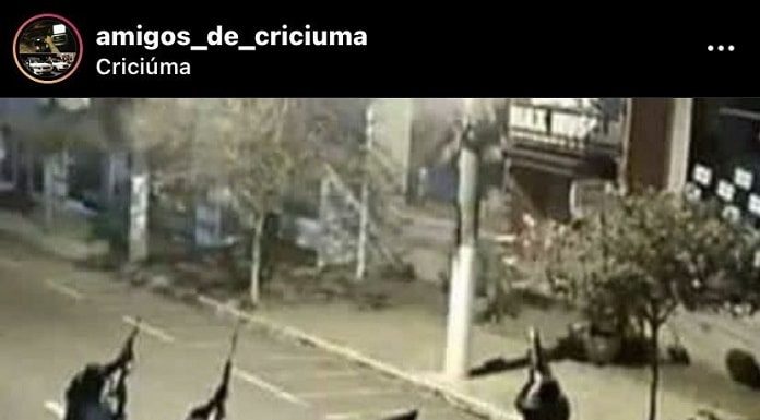 ladrões apontam metralhadoras para o alto ao lado de caminhonete com as portas abertas