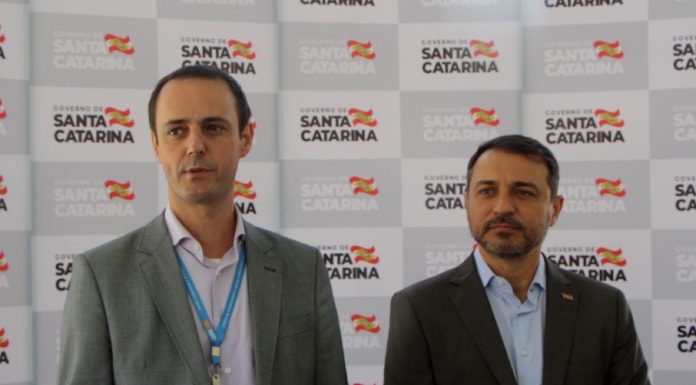 Em inauguração de subestação da Celesc em Palhoça, presidente fala de gargalos na distribuição e quadro de pessoal cleicio poleto martins e carlos moisés em entrevista coletiva; painel de logos do governo ao fundo