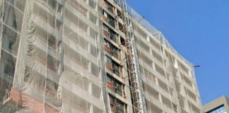 custo do metro quadrado construção civil: prédio em obras visto de baixo para cima; tela de proteção ao longo dos 10 andares
