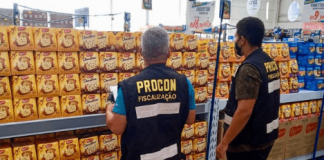 Dois fiscais do Procon de Florianópolis de costas, olhando para o preço de panettones e chocottones de um estabelecimento na capital