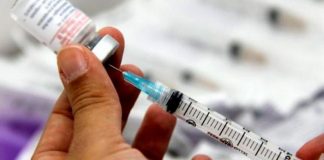 distribuição de doses de vacina à covid: pessoa retira dose de ampola com seringa