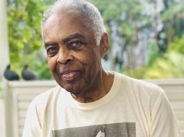 Gilberto Gil fará show na Maratona Cultural de Florianópolis gilberto gil é congratulado com título de cidadão honorário; ele olha para foto; usa camisa com foto de criança