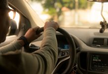 emprego uber: motorista é visto pelo ângulo do banco de trás dirigindo o carro; ele usa óculos