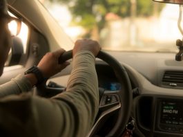 emprego uber: motorista é visto pelo ângulo do banco de trás dirigindo o carro; ele usa óculos