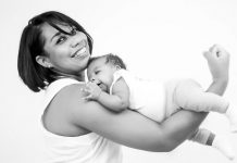Bebês e suas mães - mãe sorri para a câmera com o bebê apoiado ao longo do braços