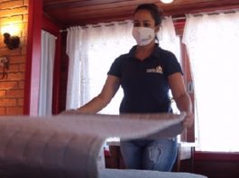 mulher usando máscara arruma uma cama de hotel - governo altera regras de serviços