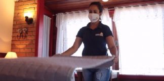 mulher usando máscara arruma uma cama de hotel - governo altera regras de serviços