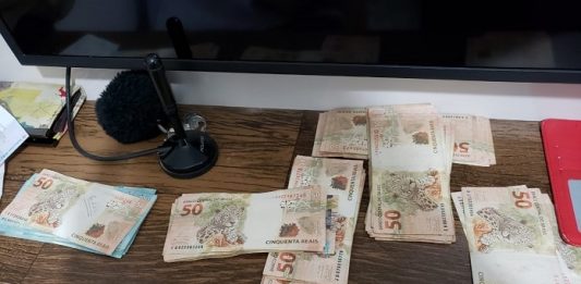 operação segunda parcela: maços de notas de 50 reais sobre bancada de televisão