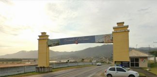 tpa de governador celso ramos - portal de entrada da cidade com montanha ao fundo; carro ao lado; estrada sob portal