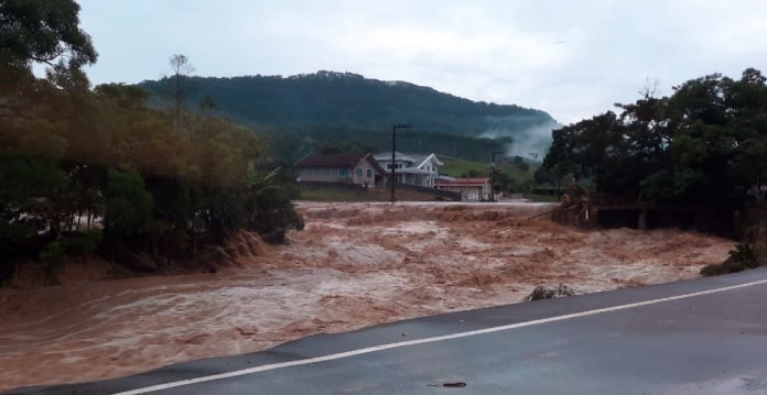 mortos em enxurrada no alto vale do itajaí: rio transbordado com forte enxurrada ao lado de estrada