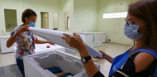 duas servidores abrem caixa de isopor para distribuição do segundo lote de vacina por região de Santa Catarina