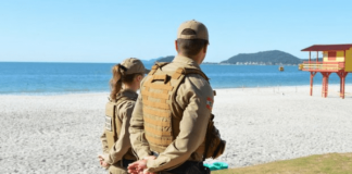 Dois policiais fardados andando na praia