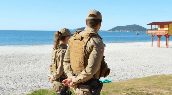Dois policiais fardados andando na praia