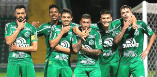 Seis jogadores da Chapecoense com uniforme verde principal, parados em fileira, fazendo pose após gol marcado pela equipe