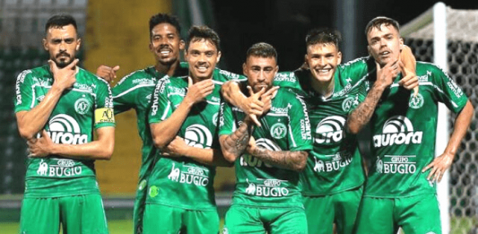 Chapecoense vence Figueirense e volta à elite do futebol nacional Seis jogadores da Chapecoense com uniforme verde principal, parados em fileira, fazendo pose após gol marcado pela equipe