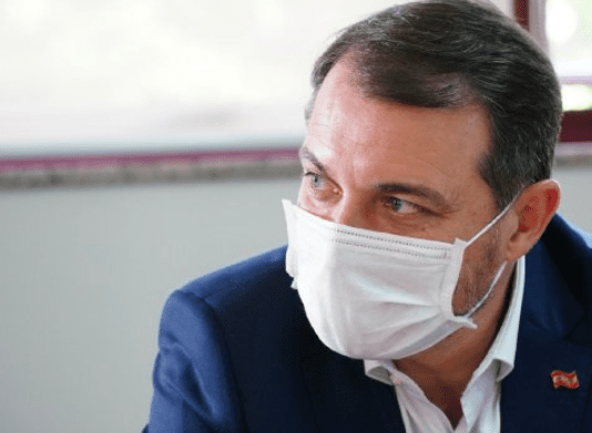 Governador Carlos Moisés no lado direito da foto, de máscara branca com olhar fixo no canto esquerdo