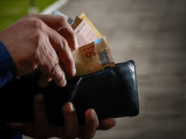 Prática abusiva do Banco C6 com clientes: Pessoa mexendo na carteira e tirando cédulas de dinheiro