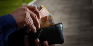 Prática abusiva do Banco C6 com clientes: Pessoa mexendo na carteira e tirando cédulas de dinheiro