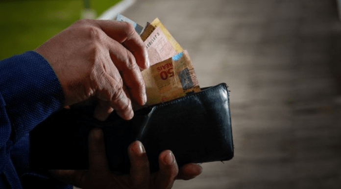 Prática abusiva do Banco C6 com clientes: Pessoa mexendo na carteira e tirando cédulas de dinheiro