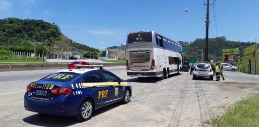 Passageiro é preso porque tentava fotografar e filmar mulher em ônibus - viatura da prf estacionada atrás do ônibus em beira de rodovia